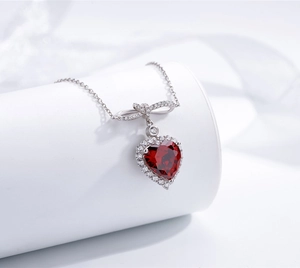 Gros plan du pendentif rubis en cœur avec nœud sur chaîne en argent sterling 925