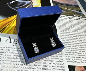 Dettaglio di orecchini rettangolari in argento 925 con zirconi gialli e scatola blu gioiello