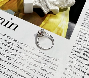 Detailed side view of 925 silver halo ring with emerald cut ruby on a fashion magazine