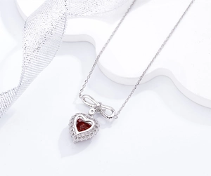 Gros plan du pendentif rubis cœur rouge sang de pigeon avec nœud en argent et chaîne