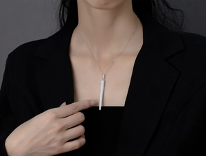 Detailed view of long silver spike pendant with micro-pave crystals on a female model