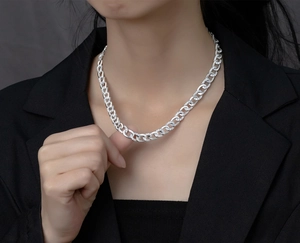 Close-up of a silver Cuban chain necklace with micro-pave crystals worn by a model