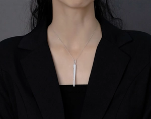 Close-up of S925 silver long tapered pendant necklace with pavé zircons on a model