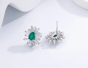 Macro detail of S925 silver stud earrings with pear cut emerald and baguette diamonds