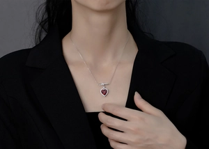 Détail du collier cœur rouge sang de pigeon avec nœud sur le cou du mannequin