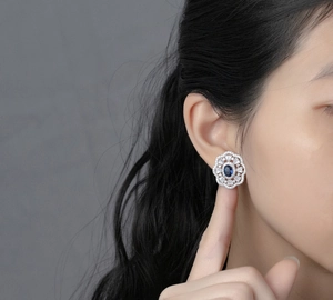 Macro detail of royal blue oval gemstone earrings with floral micro-pave diamond setting
