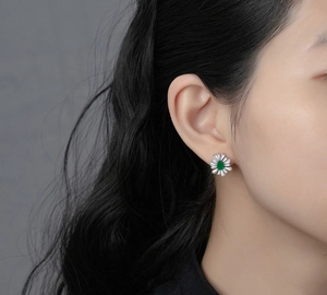 Close-up of elegant flower-shaped emerald stud earrings with diamonds on ear