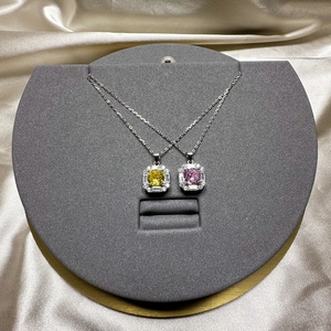 Quadratische Silberhalsketten mit gelben und rosa Steinen auf champagnerfarbenem Satin
