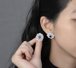 Detailed close-up of oval blue sapphire earrings with floral diamond cluster setting