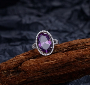 Détail macro d'une bague avec améthyste ovale et halo de diamants sur bois brut