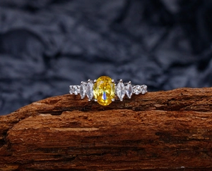 Macro detail of oval yellow diamond ring with marquise side stones on wood texture
