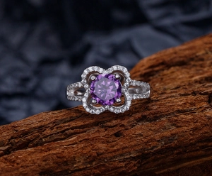 Macro shot of 925 sterling silver ring with purple flower stone on wooden bark