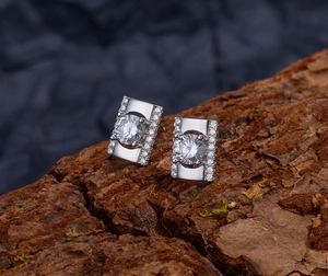 Gros plan de boucles d'oreilles géométriques en argent avec pierre ronde sur bois texturé