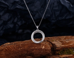Close-up of S925 silver Mobius pendant with cubic zirconia on textured wood background