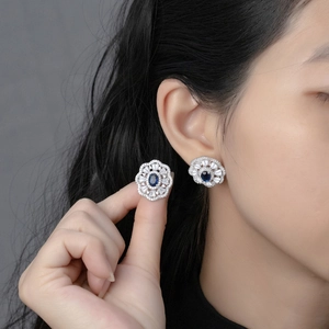 Vintage oval royal blue sapphire stud earrings with radiating diamond halo on model
