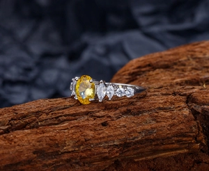 Detailed close-up of 925 sterling silver ring with oval yellow stone on rustic wood