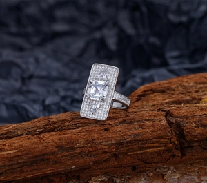 Dettaglio macro dell'anello con taglio a smeraldo e pavé di diamanti su legno grezzo