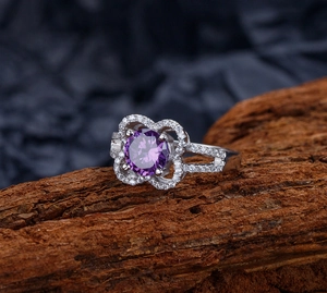 Macro view of purple gemstone flower ring with micro-paved crystals on dark wood base