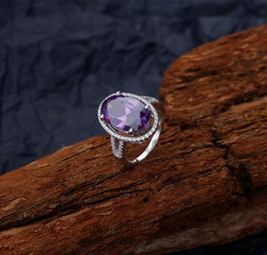 Vue macro d'une bague avec pierre précieuse violette et halo de diamants sur écorce