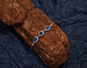 Macro shot of silver bracelet with oval blue sapphires resting on a natural wooden block