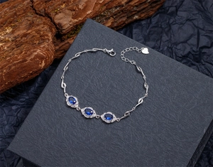 Gros plan d'un bracelet en argent S925 avec saphirs bleus ovales et breloque coeur réglable