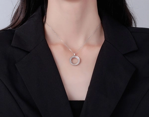 Polished silver Mobius double ring necklace on a model wearing a black blazer suit