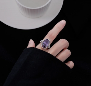 Gros plan détaillé d'une bague améthyste ovale violette portée avec halo scintillant