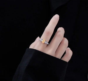 Detailed view of an oval yellow gemstone ring on a finger with a dark background