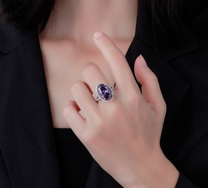 Gros plan d'une bague en argent 925 avec pierre violette ovale et halo de diamants
