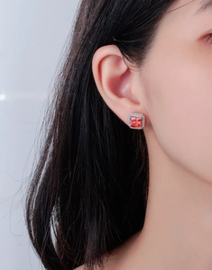 Gros plan d'une boucle d'oreille carrée avec rubis sur l'oreille du modèle