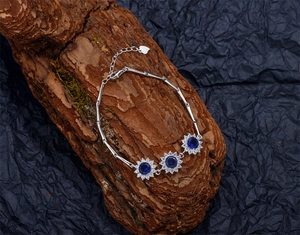 Détail du bracelet tournesol en argent 925 avec saphirs bleus sur fond d'écorce rustique
