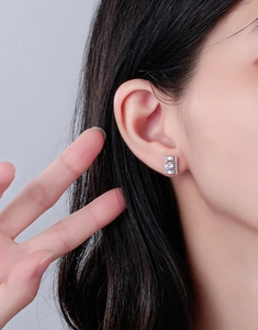 Gros plan de boucles d'oreilles carrées en diamant portées sur l'oreille pour un luxe discret