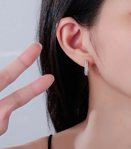 Detailed close-up of Mobius silver earrings with sparkling zircon pave set on the earlobe