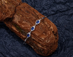 Détail de trois saphirs bleus ovales sertis sur bracelet en argent avec pavage