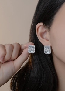 Close-up of mother of pearl square earrings with micro-inlaid diamonds and cloud motif