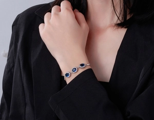 Macro shot of silver bracelet with oval blue sapphire stones and halo setting zircons
