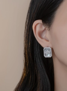 Macro view of rectangular silver earring with mother of pearl and crystal clover detail