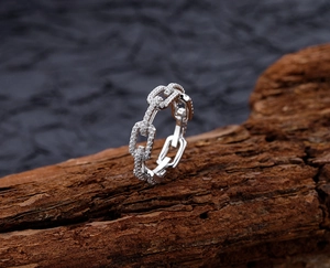 Close-up of S925 silver chain ring with white pavé zircons on a rustic wooden base