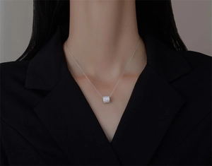 Classic cylinder pendant necklace with sparkling micro-pave crystals on a black blazer suit
