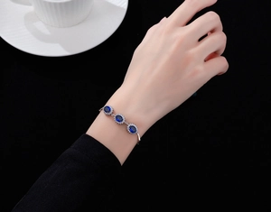 Detail of S925 silver bracelet with oval blue sapphire stones and zircon accents