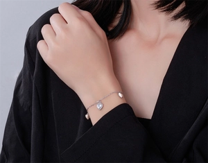 Gros plan du bracelet cœur en argent avec pierres étincelantes au poignet