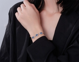 Gros plan du bracelet en saphir bleu avec halo de diamants sur le poignet d'un mannequin