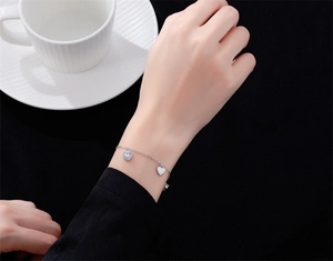 Gros plan d'un bracelet cœur en argent S925 avec zircons sur le poignet d'un modèle
