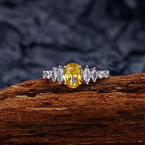 Elegant silver ring with oval yellow gemstone and white zircons on wooden block