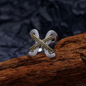 Crossed S925 silver ring with gold plating and paved zircon stones on a wooden stand