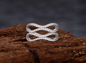 Detailed view of silver infinity wave ring with pavé diamonds on natural wood bark