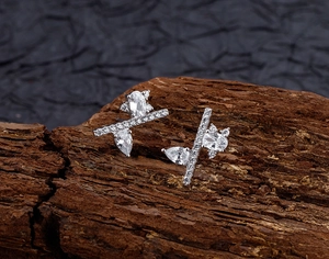 Macro detail of S925 sterling silver asymmetrical earrings with inlaid zircons on wood