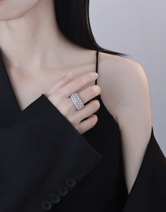 Macro shot of a sparkling V-shaped wide band silver ring with pave-set zircons on a model