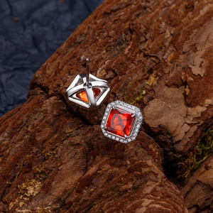 Boucles d'oreilles carrées avec pierre orange et halo sur fond de bois rustique