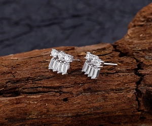 Macro shot of silver stud earrings with round and baguette cut zircons on wood